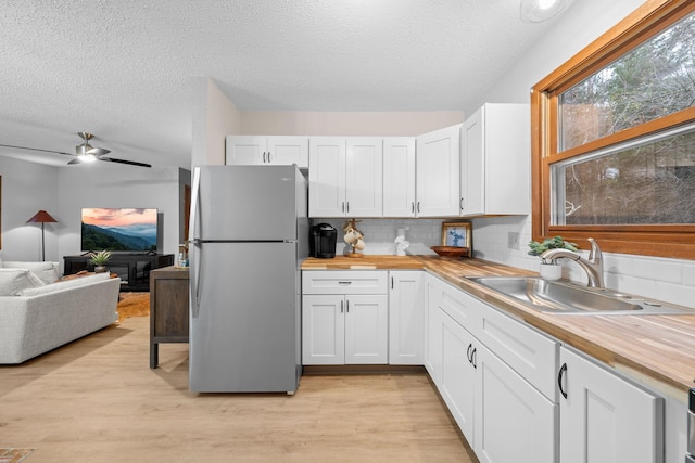 23245 County Rd W, Grantsburg, WI 54840 - kitchen with freestanding refrigerator, butcher block countertops, a sink, a textured ceiling, and white cabinetry
