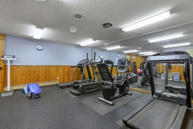 exercise room with wooden walls, a textured ceiling, and visible vents