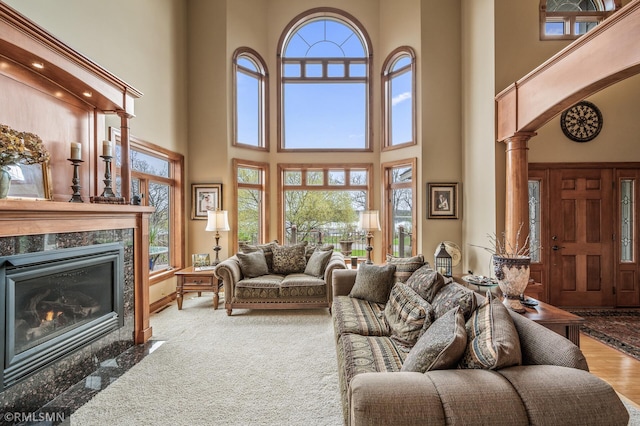 living room with a premium fireplace, ornate columns, and a towering ceiling