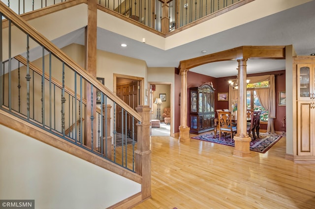 entrance foyer with stairs, wood finished floors, ornate columns, a high ceiling, and recessed lighting