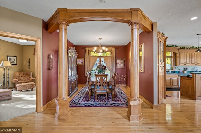 dining space with a notable chandelier, baseboards, decorative columns, and light wood finished floors