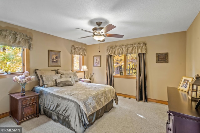 bedroom featuring a textured ceiling, baseboards, light colored carpet, and ceiling fan