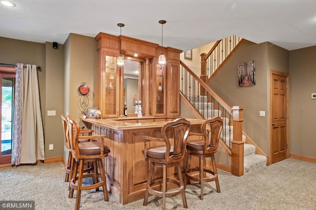 bar featuring baseboards, wet bar, light carpet, and stairway