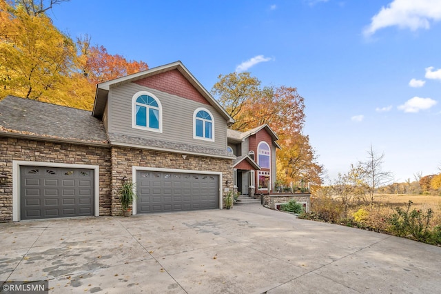 view of front of house with an attached garage, stone siding, and concrete driveway