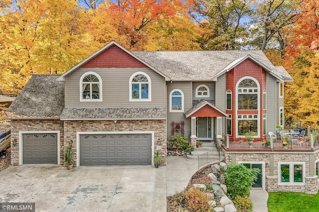 view of front of home featuring roof with shingles, an attached garage, concrete driveway, and stone siding