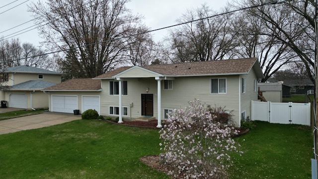 bi-level home with an attached garage, a front lawn, fence, and driveway