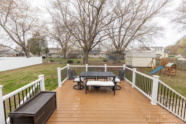 wooden terrace featuring a residential view, a storage unit, outdoor dining area, a lawn, and an outdoor structure