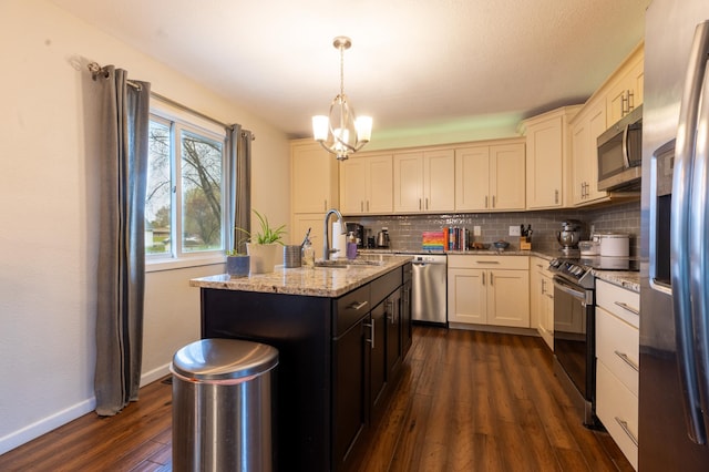kitchen with a notable chandelier, appliances with stainless steel finishes, a sink, tasteful backsplash, and dark wood-type flooring
