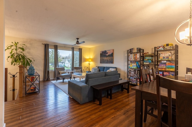 living area featuring dark wood-style floors and ceiling fan with notable chandelier