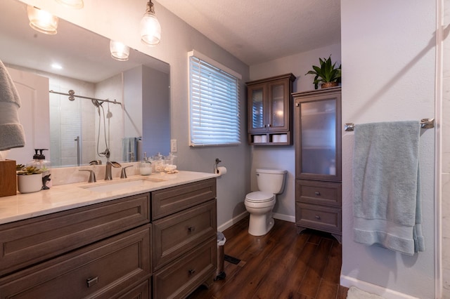full bath featuring vanity, wood finished floors, toilet, baseboards, and a stall shower