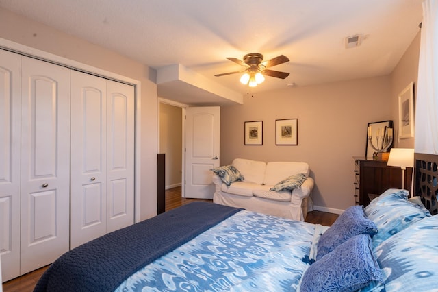 bedroom featuring a ceiling fan, baseboards, wood finished floors, visible vents, and a closet