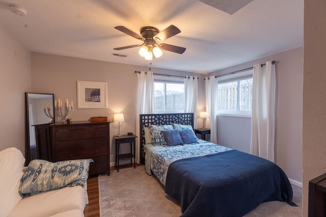 bedroom featuring a textured ceiling, visible vents, ceiling fan, and wood finished floors