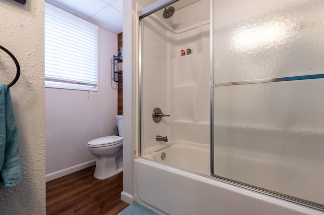 full bath featuring a textured wall, toilet, baseboards, wood finished floors, and bath / shower combo with glass door
