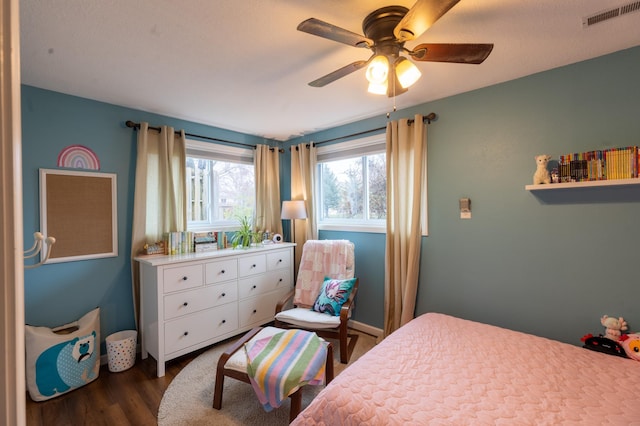 bedroom with ceiling fan, dark wood-style floors, and visible vents