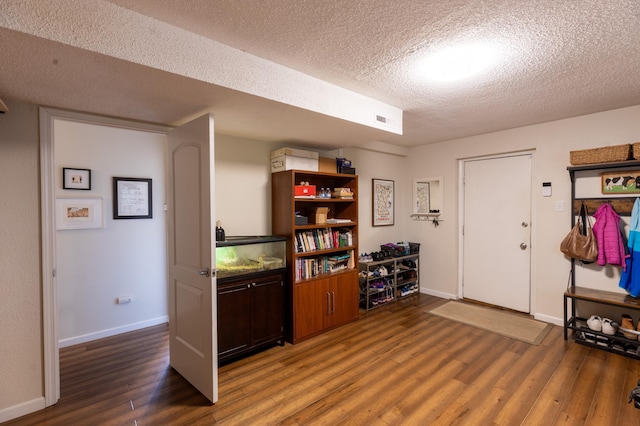interior space featuring baseboards, a textured ceiling, visible vents, and wood finished floors