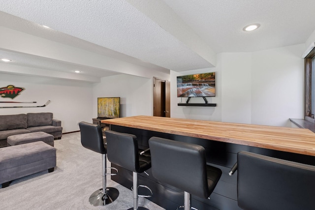 bar featuring light colored carpet, recessed lighting, a textured ceiling, and a bar