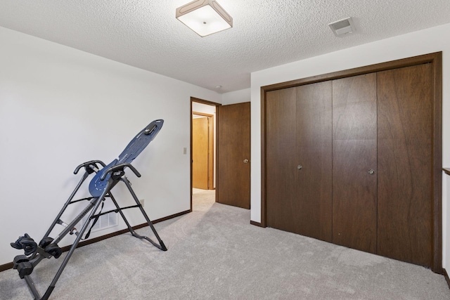 exercise room featuring visible vents, a textured ceiling, baseboards, and light carpet