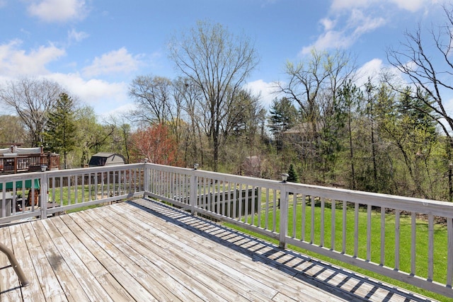 wooden terrace featuring a yard, a shed, and an outbuilding