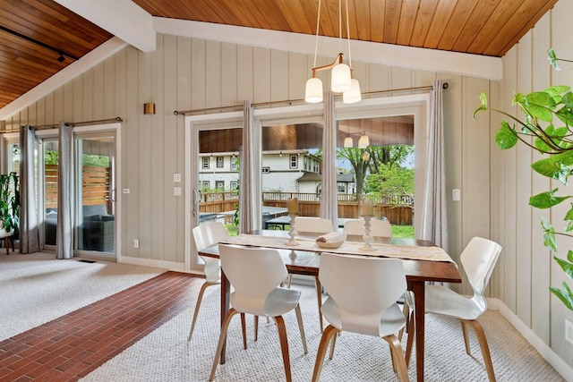 dining space featuring healthy amount of natural light, baseboards, wooden walls, wood ceiling, and brick patterned flooring