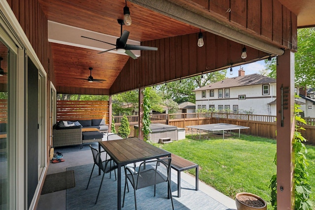 view of patio / terrace featuring ceiling fan, a hot tub, an outdoor hangout area, a trampoline, and outdoor dining space