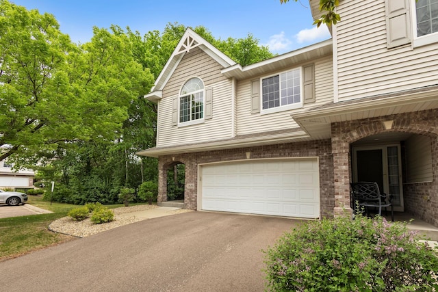 view of front of house with an attached garage, asphalt driveway, and brick siding