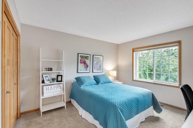 bedroom featuring light carpet, a textured ceiling, and baseboards