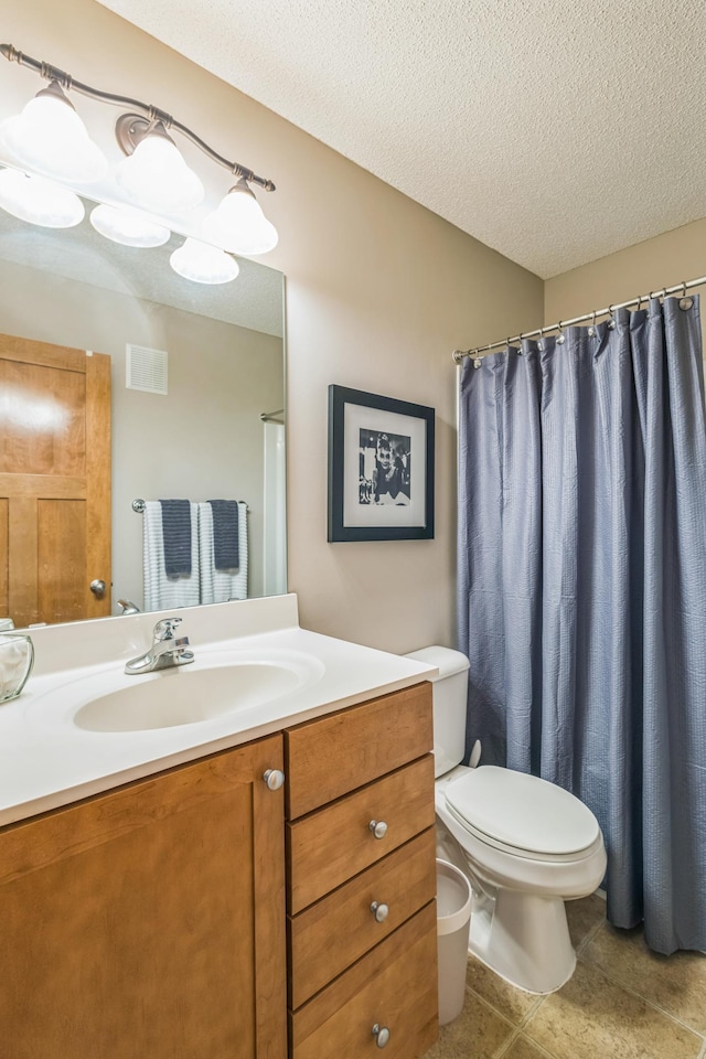 bathroom with toilet, vanity, a textured ceiling, and tile patterned flooring