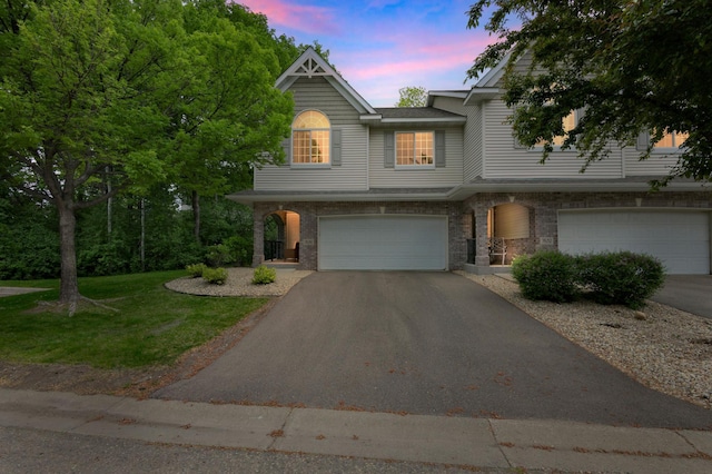 view of property with asphalt driveway, an attached garage, a front lawn, and brick siding