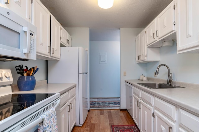 kitchen with white appliances, a sink, white cabinetry, light wood-style floors, and light countertops