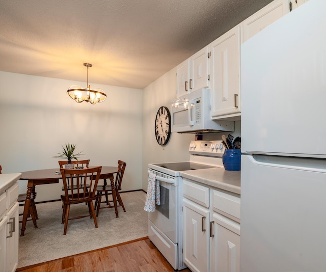 kitchen with light wood finished floors, white cabinets, white appliances, light countertops, and a chandelier