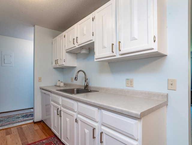 kitchen with white cabinets, light wood-type flooring, a sink, and dishwasher