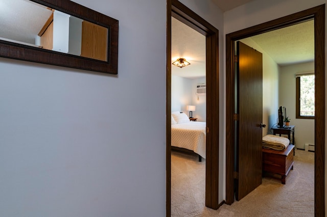 hallway featuring light carpet, a wall unit AC, and a baseboard heating unit