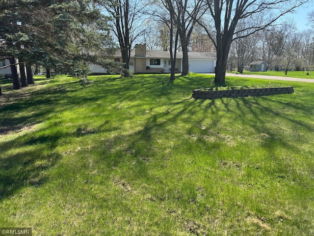view of yard featuring driveway and a garage