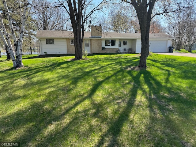 ranch-style house featuring an attached garage, driveway, a chimney, and a front yard