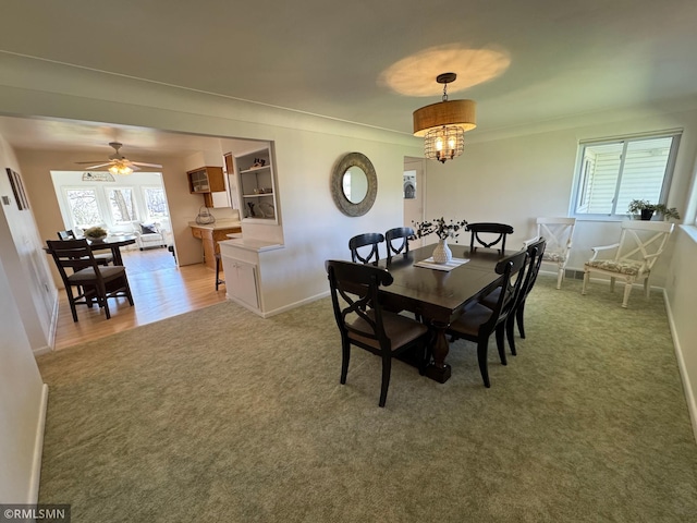 dining area featuring baseboards, light carpet, ornamental molding, and a ceiling fan