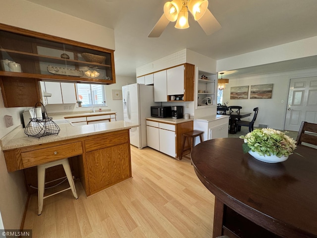 kitchen featuring white refrigerator with ice dispenser, black microwave, open shelves, light wood-style floors, and light countertops