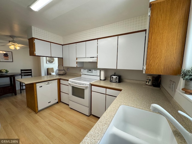 kitchen with a sink, white appliances, under cabinet range hood, ceiling fan, and light countertops
