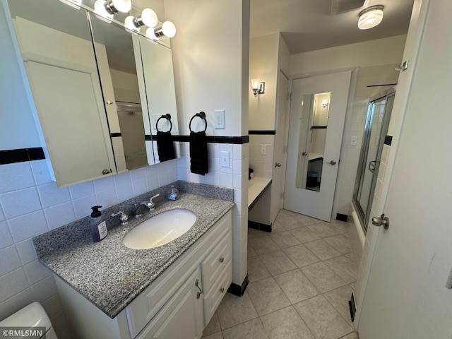 full bath featuring tile patterned floors, tile walls, a shower with door, and vanity