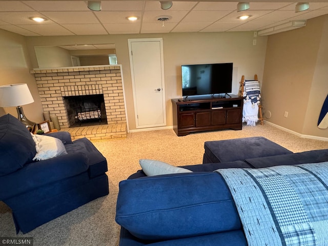 carpeted living room with a drop ceiling, baseboards, and a fireplace