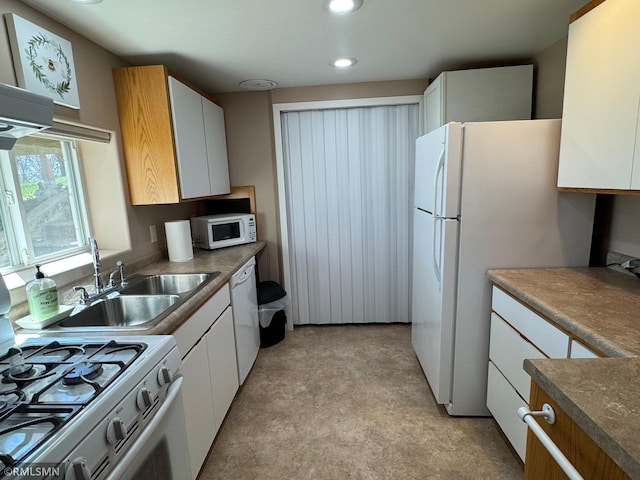 kitchen with a sink, white appliances, white cabinets, and recessed lighting