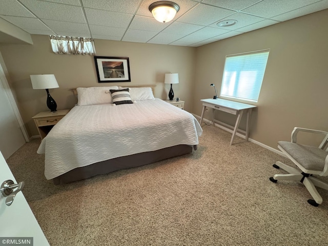 carpeted bedroom with a paneled ceiling and baseboards