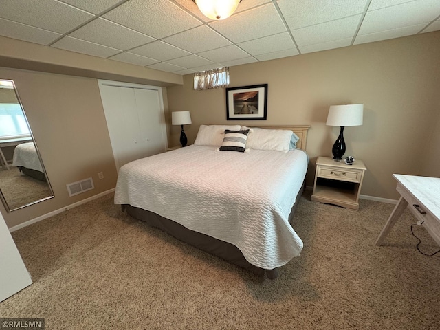 bedroom with carpet, a closet, a paneled ceiling, visible vents, and baseboards