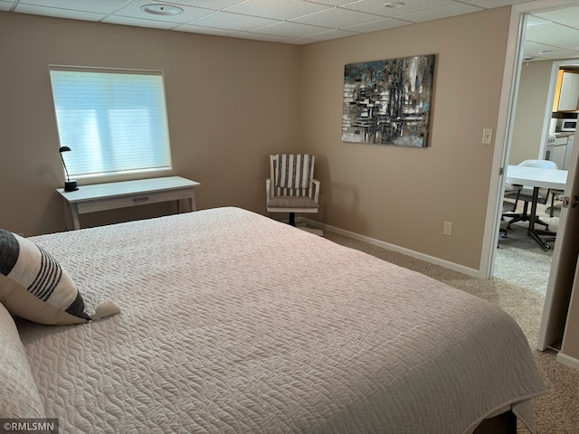 bedroom featuring baseboards, a drop ceiling, and carpet