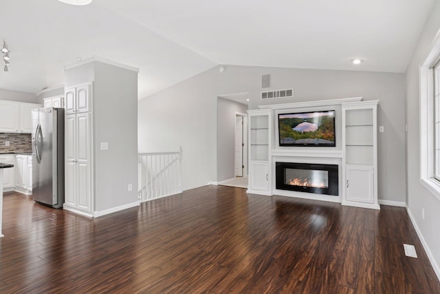unfurnished living room featuring visible vents, dark wood-style flooring, a glass covered fireplace, lofted ceiling, and baseboards