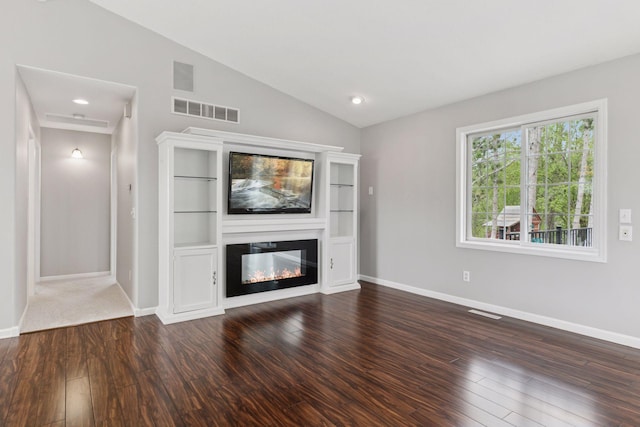 unfurnished living room with baseboards, vaulted ceiling, wood finished floors, and visible vents