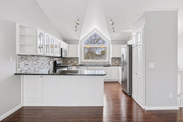 kitchen featuring dark countertops, vaulted ceiling, a sink, a peninsula, and stainless steel appliances