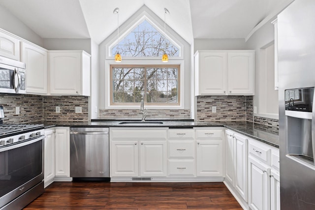 kitchen with plenty of natural light, a sink, appliances with stainless steel finishes, and lofted ceiling