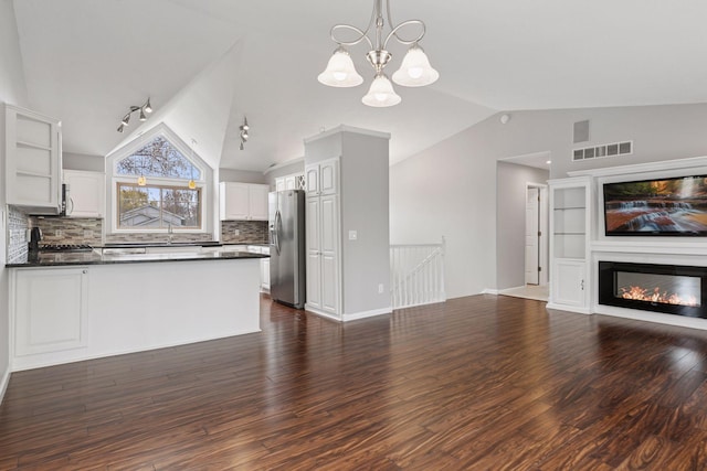 unfurnished living room with a chandelier, vaulted ceiling, dark wood-style floors, and visible vents