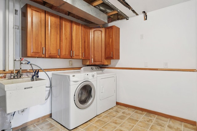 clothes washing area featuring baseboards, a sink, cabinet space, and washing machine and clothes dryer