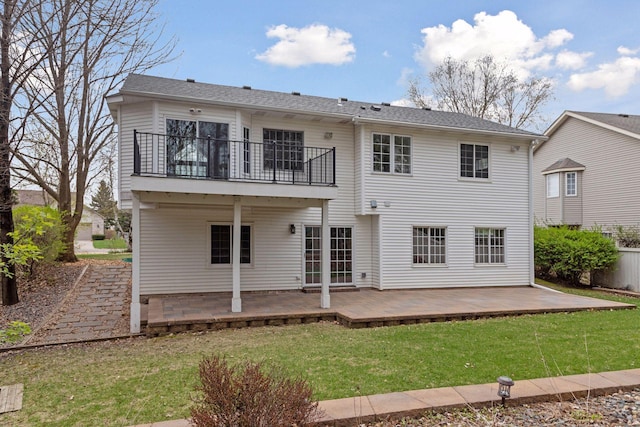rear view of house with a patio area, a yard, and a balcony